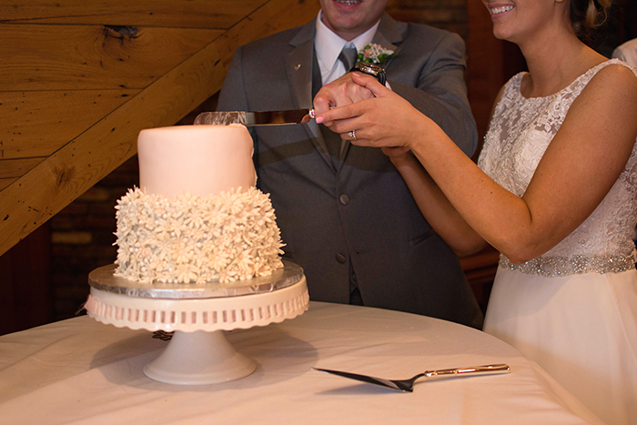 Stacey & Eric - A Cozy Ohio Wedding | Love is All you Need Photography | As seen on TodaysBride.com | Ohio real wedding, wedding cake, cutting the cake, floral wedding cake