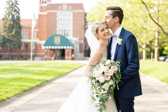 Smiling bride with groom kissing her forehead | Sabrina Hall Photography | As seen on TodaysBride.com