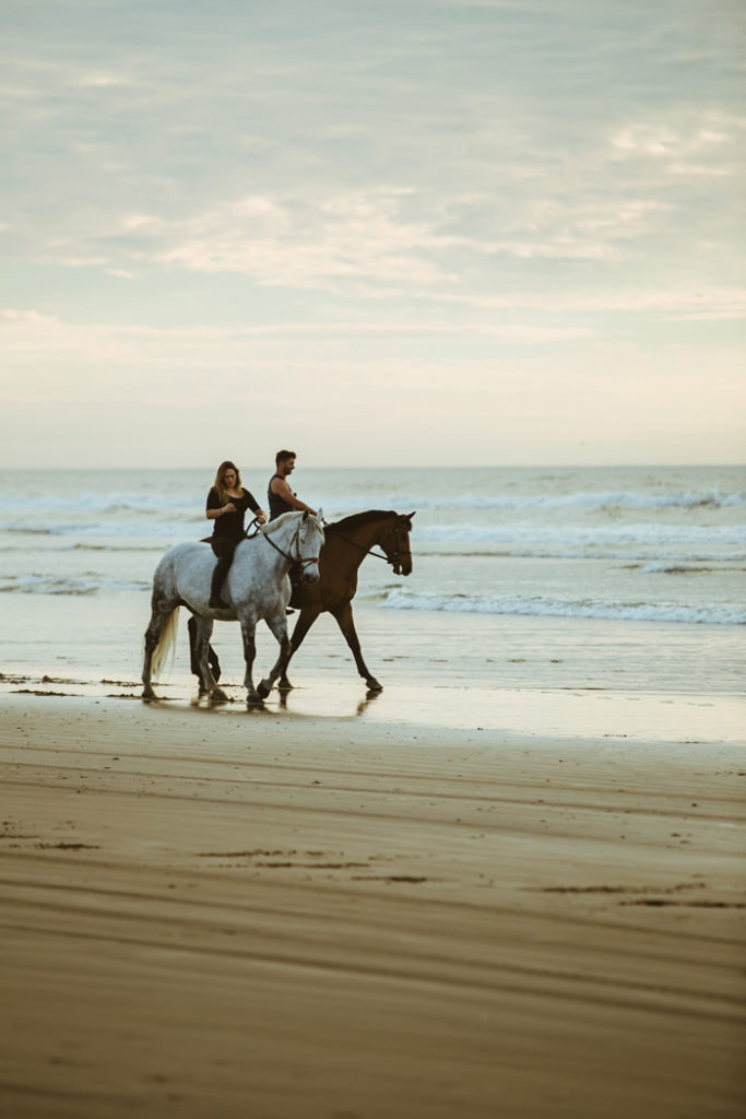 Couple riding horses on the beach | As seen on TodaysBride.com