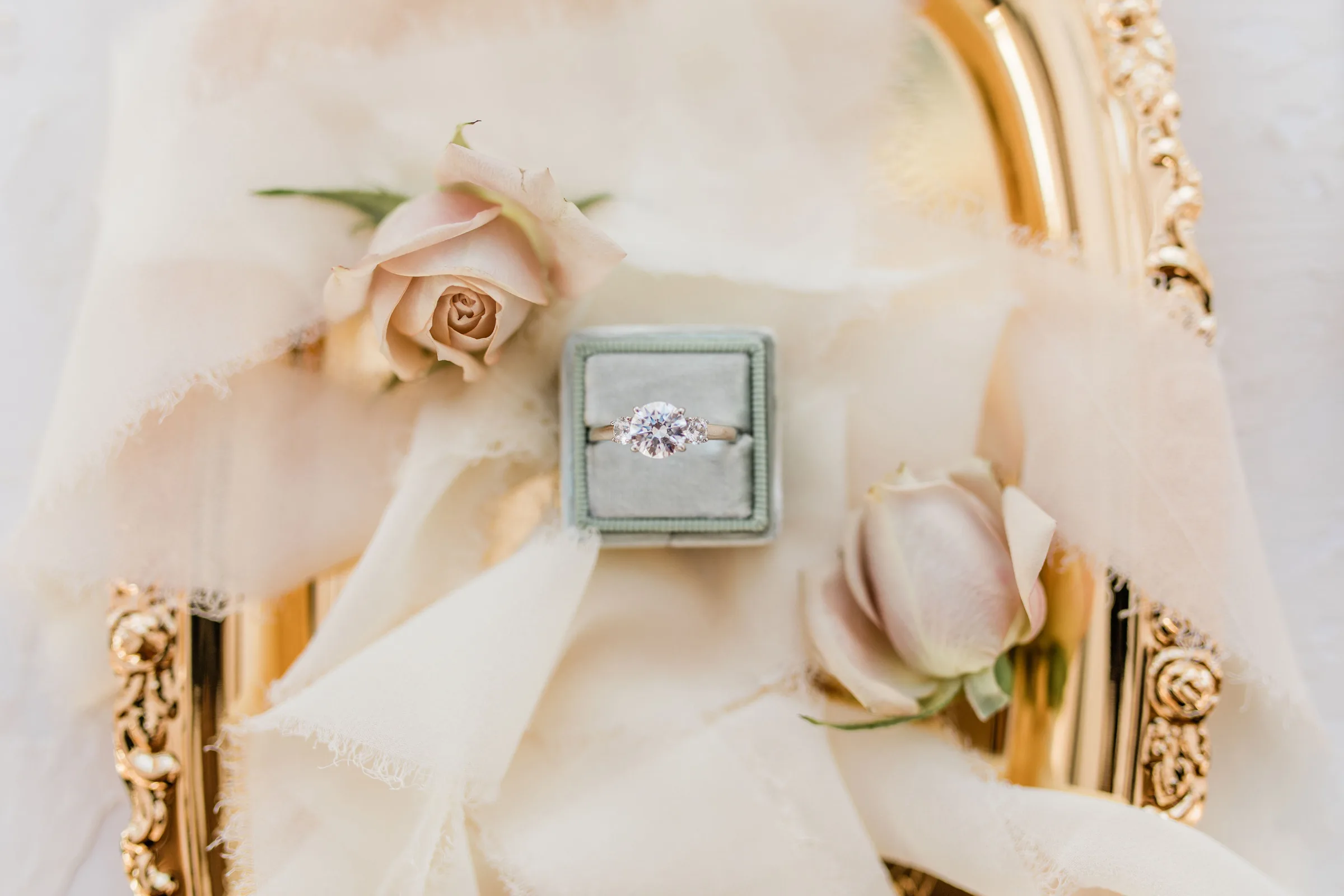 engagement ring in ring box sitting on tray with ribbon and roses