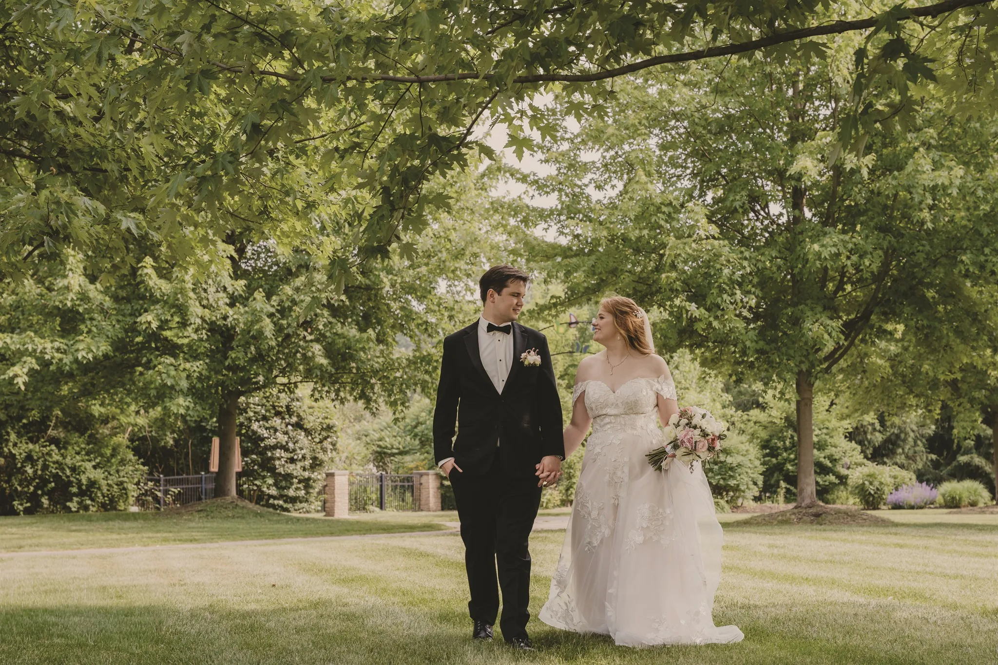 bride and groom walking outside in a greenery area